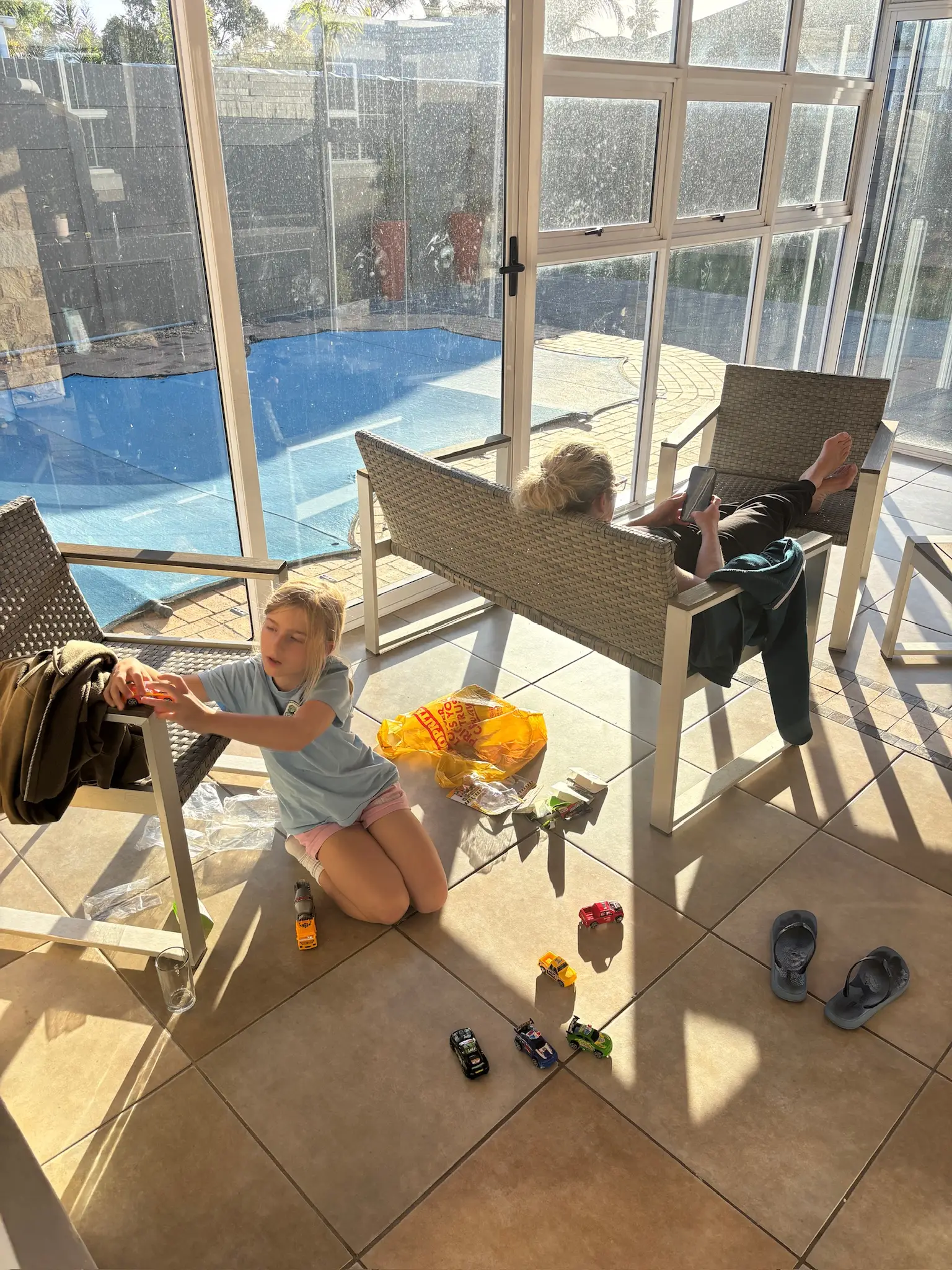 Merle spielt auf der Terrasse, dahinter der Pool